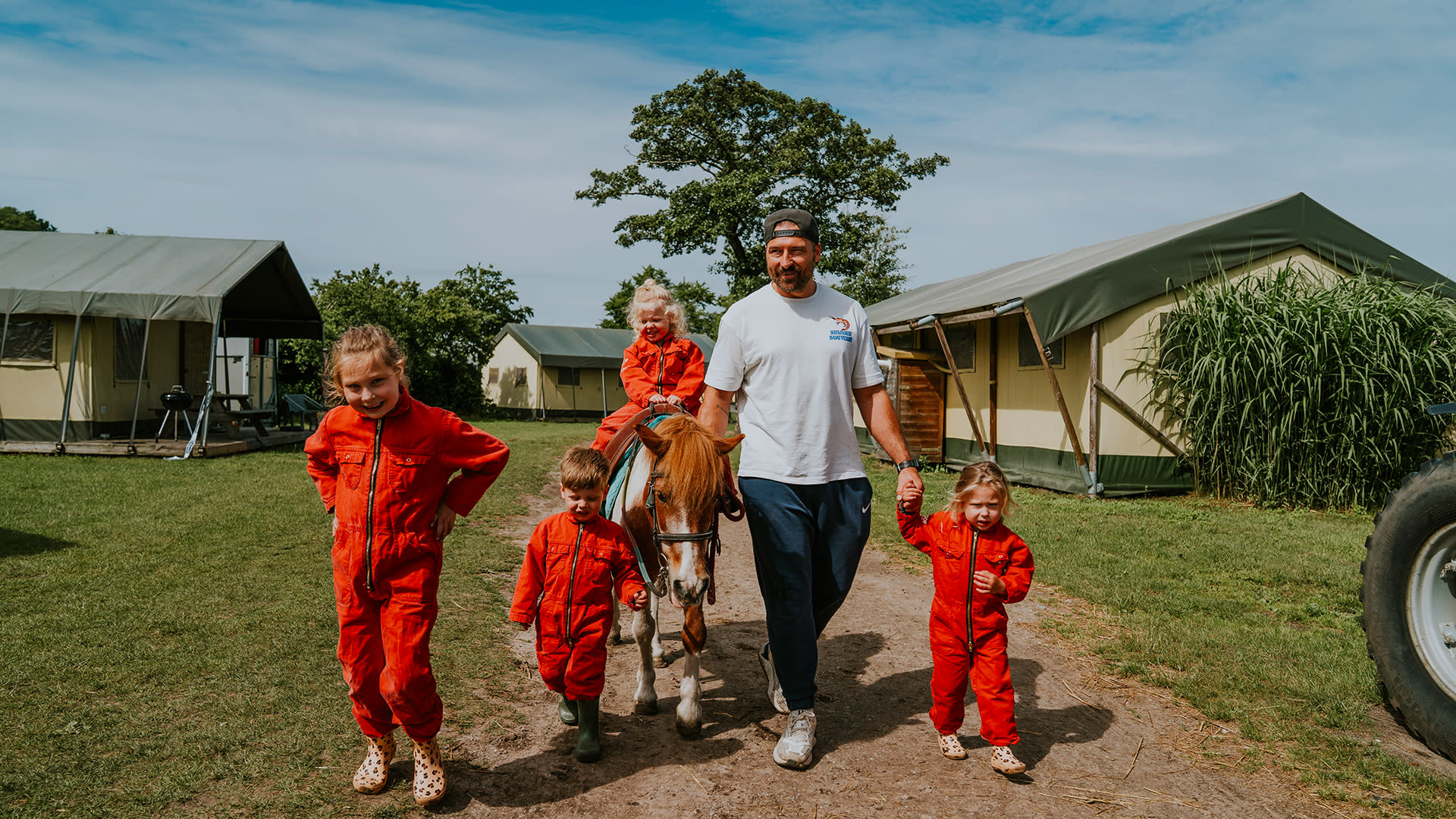 Kinderen met een pony en een volwassene tussen de glampingtenten van FarmCamps Breehees