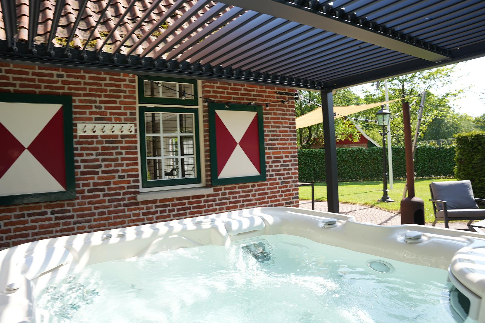 Bubbelende jacuzzi onder de pergola naast De Brittenburg