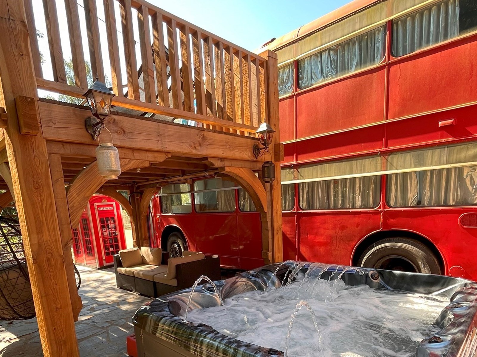 Privéjacuzzi naast de rode dubbeldekker, onder het houten terras