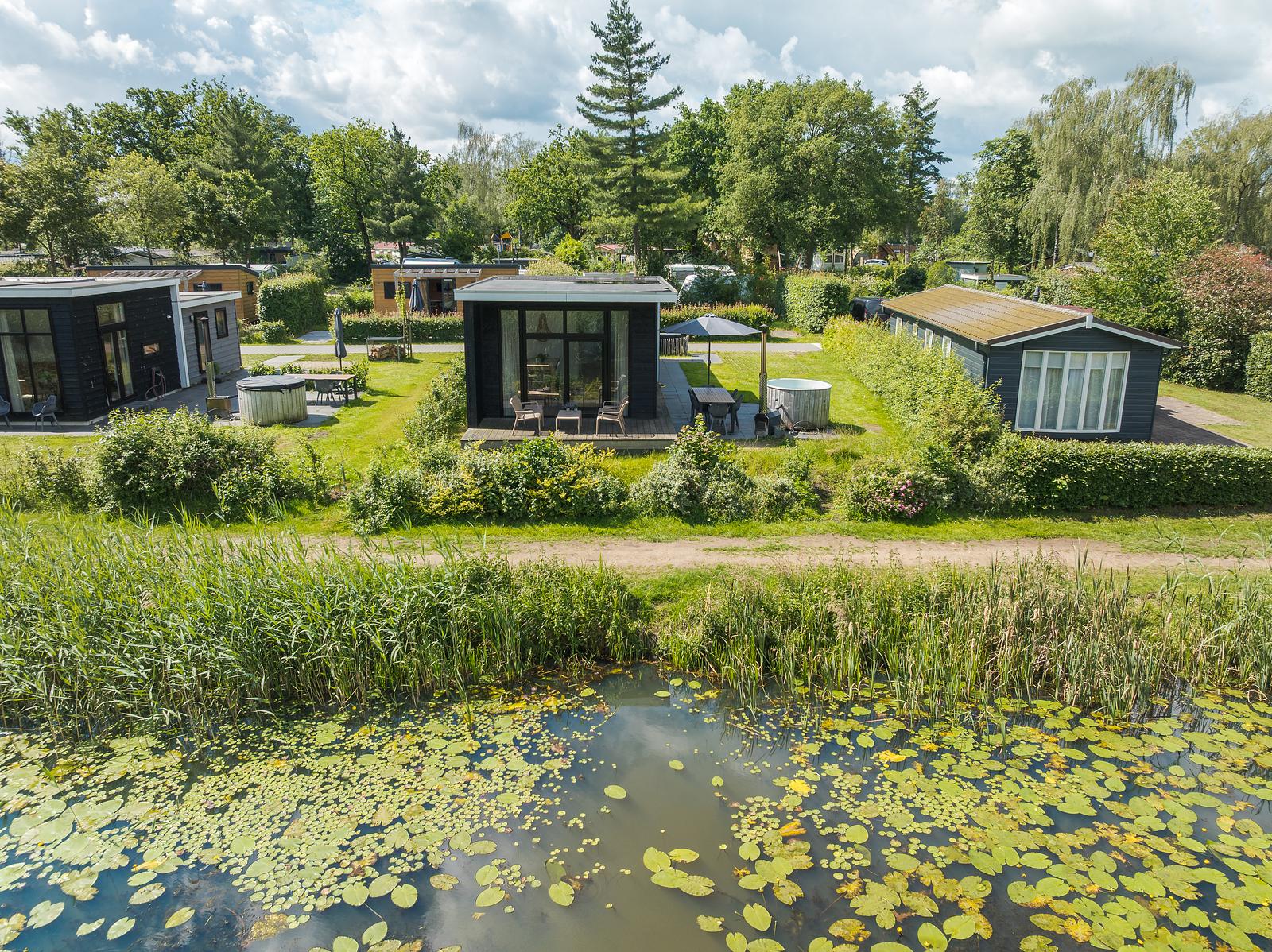 River Cabin met terras en ronde hottub achter de met riet begroeide rivieroever